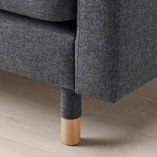 Primer plano de una pata de sofá moderna, hecha de madera y tela, sobre un suelo de madera.