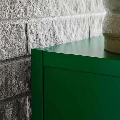 Armario verde brillante junto a una pared de ladrillo blanco.