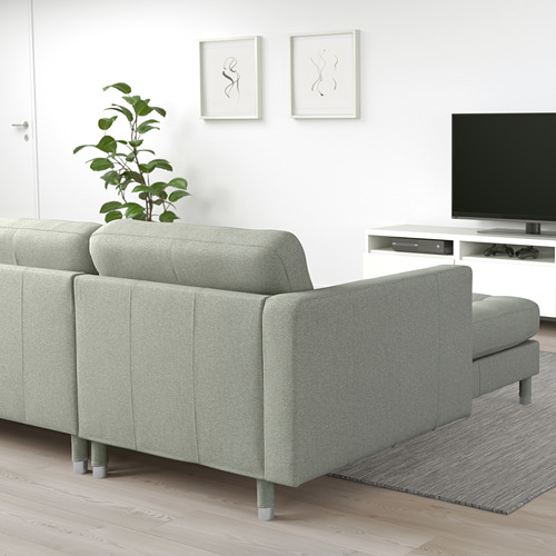 Sala de estar moderna con sofá landsskrona verde claro, alfombra gris, planta, televisión, decoración minimalista.
