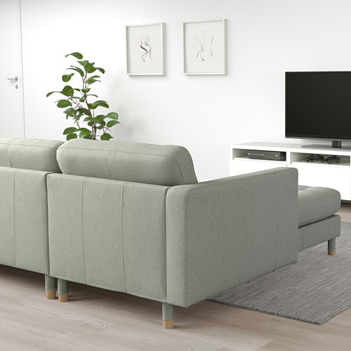 Moderno sofá gris claro con tumbona, tela cuidada, patas de madera en acogedora sala de estar.