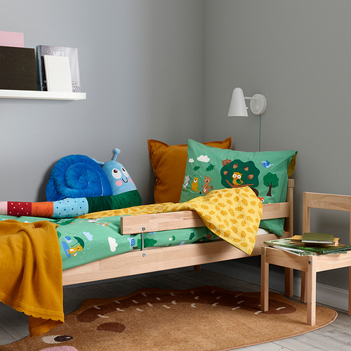 Habitación para niños con cama de madera, almohadas de colores, juguetes, libros y alfombra de erizo BRUMMIG.