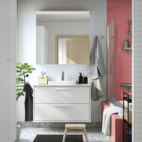 Baño moderno con mueble de encimera TOLKEN blanco, lavabo blanco, espejo, toallas grises, decoración en blanco y negro y ducha con azulejos rojos.