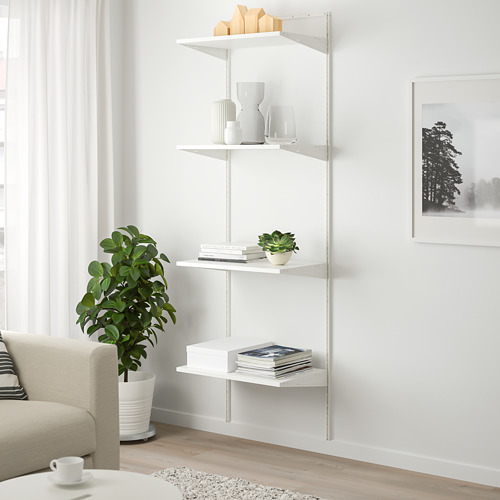 Estantería BOAXEL blanca, de diseño minimalista, con libros, jarrones y una planta, junto a un sofá color crema y un gran ventanal.