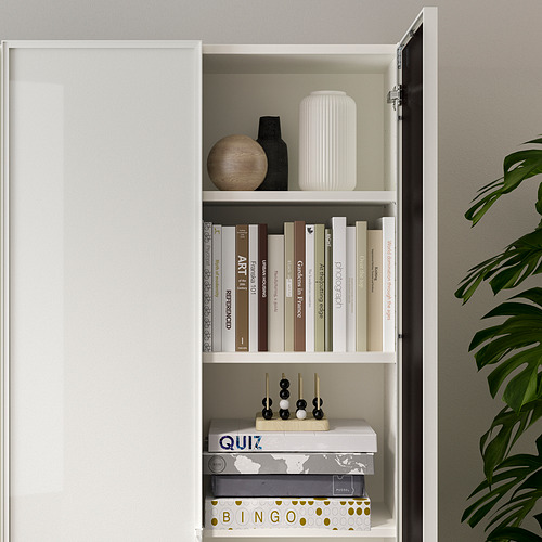Librería blanca BILLY con puertas de cristal, donde se exhiben libros, objetos decorativos y juegos. Los estantes son ajustables.