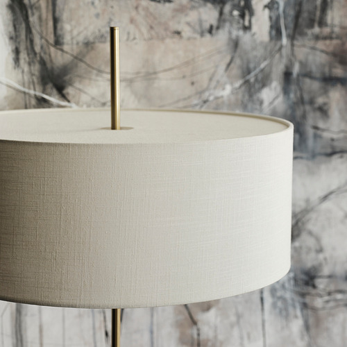 Gran lámpara de pie moderna con pantalla blanca texturizada sobre un robusto poste de latón. Diseño elegante y minimalista.