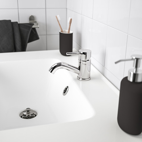 El soporte para cepillos de dientes negro se encuentra junto al moderno grifo cromado, pequeño para un espacio limitado en el mostrador.