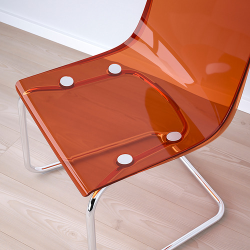 Silla moderna transparente naranja con patas cromadas, diseño elegante, asiento flexible, sobre suelo de madera clara.