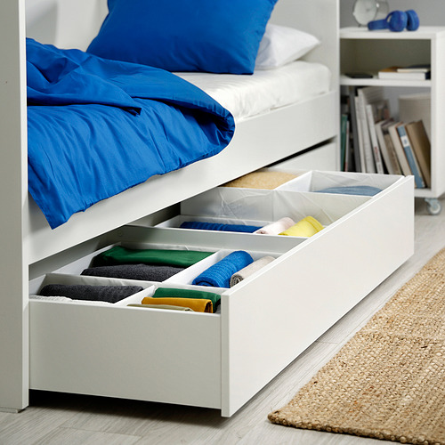 Cajones de almacenamiento debajo de la cama con ropa doblada codificada por colores, lo que maximiza el espacio.