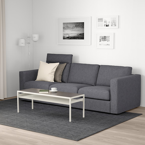 Salón moderno: sofá VIMLE gris con almohadas, mesa de centro blanca, alfombra y arte de pared.