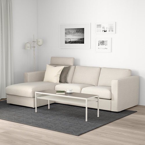 Sala de estar moderna con sofá beige VIMLE, mesa de centro blanca, alfombra gris y arte de pared.