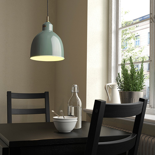 Rincón de cocina moderno con lámpara colgante RÖDFLIK verde azulado, que proyecta luz sobre la mesa con sillas, planta y ventana.