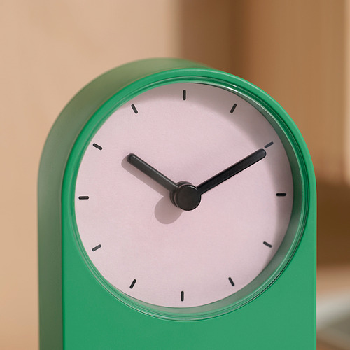 Reloj verde sencillo con acabado liso y manecillas negras finas, sobre un fondo neutro.