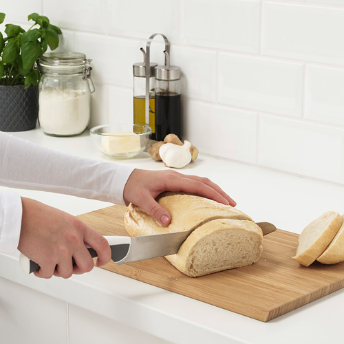 La persona rebana el pan con un cuchillo en una tabla de cortar en la cocina.