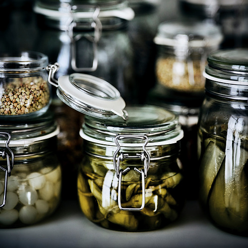 Varios frascos de vidrio con abrazaderas de metal almacenan encurtidos y otros alimentos en conserva. Los frascos tienen sellos herméticos, lo que garantiza la frescura.