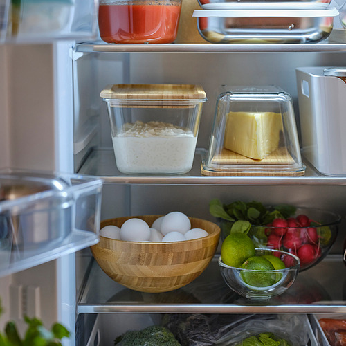 Refrigerador abierto con recipientes transparentes que contengan avena, mantequilla y fruta.