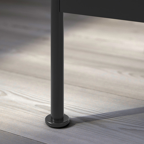 Moderna pata de mesa de metal negro con base circular sobre suelo de madera.
