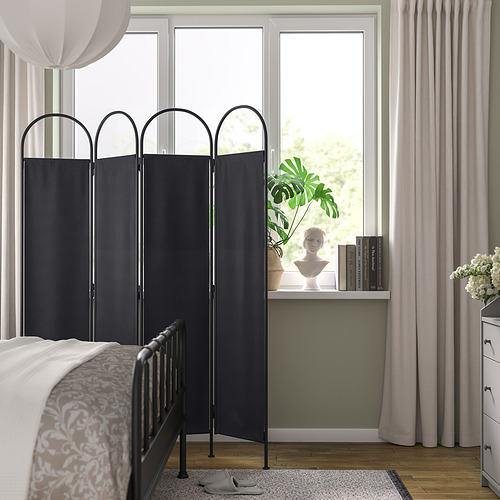 Dormitorio con separador GRÅFJÄLLET negro, cama, escritorio, estatua, planta, tocador, grandes ventanales.