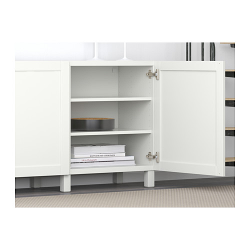 White BESTÅ sideboard with adjustable shelves and soft-closing doors, shown open with stacked books inside.