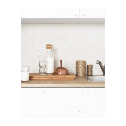 Moderna encimera de cocina blanca con azulejos hexagonales, encimera de madera, artículos de cobre, vasos y fregadero.