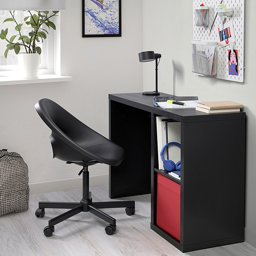 Un escritorio KALLAX negro compacto con una caja roja y auriculares azules. Tiene un diseño elegante, adecuado para espacios pequeños.