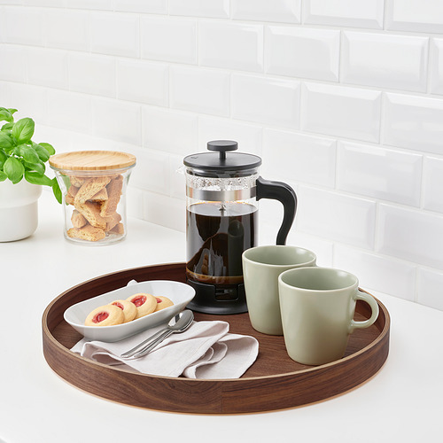Bandeja de madera con prensa francesa negra, dos tazas verdes, galletas y utensilios, perfecta para servir y decorar.