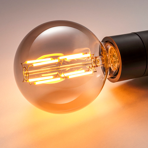 Bombilla led de globo con ocho filamentos incandescentes en vidrio ahumado, que emiten una luz cálida.