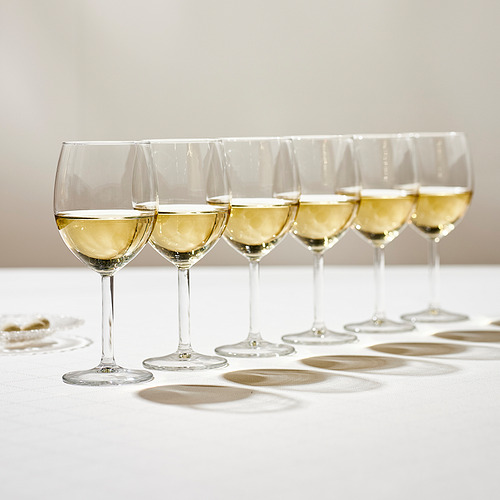 Seis copas de vino, cada una llena de vino blanco, se alinearon cuidadosamente sobre un mantel blanco, realzando los aromas y sabores del vino.