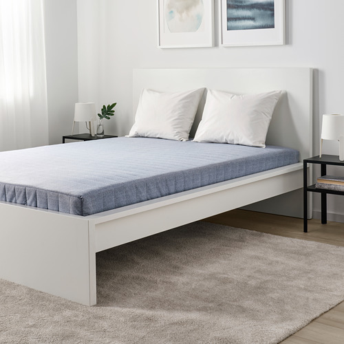 Dormitorio moderno con cama blanca, alfombra gris, mesitas de noche negras y decoración minimalista.