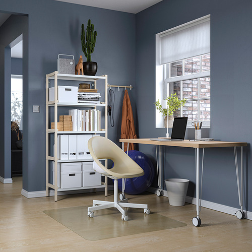 Moderna oficina en casa con escritorio, silla y estantería LAGKAPTEN blancos contra la pared azul oscuro.