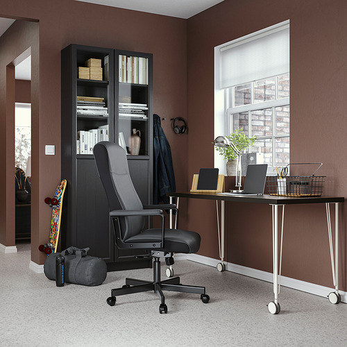 Home office setup with black LAGKAPTEN desk, ergonomic chair, bookcase, and laptop.