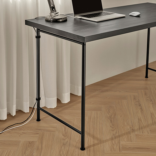 Moderna configuración de escritorio con computadora portátil, mouse y lámpara, con patas ajustables para mayor estabilidad en pisos irregulares, marco de metal negro y elegante tapa de madera.