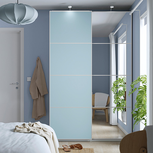 Dormitorio moderno con armario PAX azul, puertas corredizas de vidrio, plantas y cama blanca.
