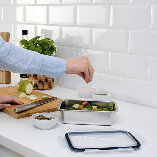 La persona prepara la ensalada en un recipiente de acero inoxidable para ikea en la encimera de la cocina.