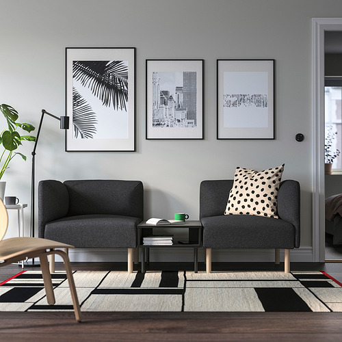 Sala de estar moderna con mesa TUNSTA, sofás, obras de arte, plantas y alfombras.