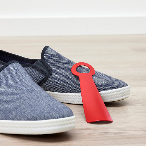Zapatillas azules con calzador rojo insertado, sobre suelo de madera.