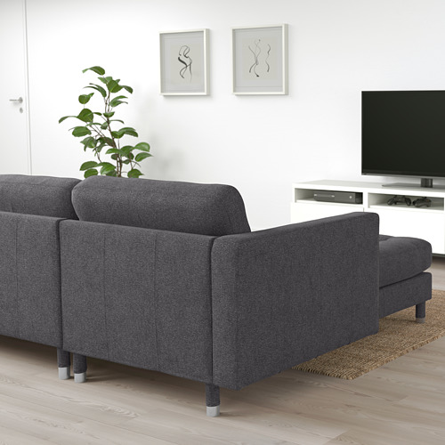 Sofá modular moderno de tela gris, grande, con reposabrazos, contra pared blanca, cerca de la televisión.