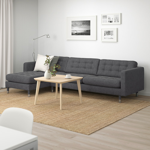 Moderno sofá gris en salón minimalista con suelo de madera y alfombra de yute.