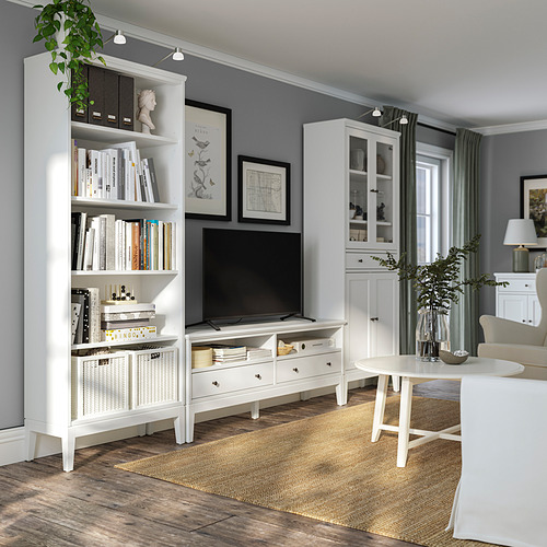 Disposición del salón IDANÄS en blanco: moderno, de madera, estanterías, mueble de TV, cajones de cierre suave, paredes gris claro, alfombra, sillas acolchadas, armario de cristal.