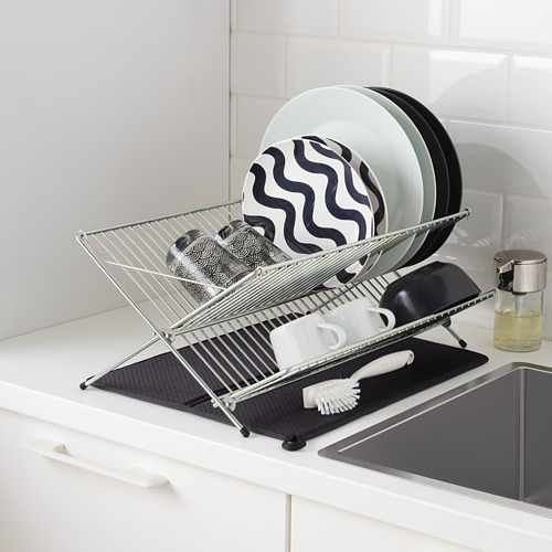 Estante de platos de metal en una encimera de cocina con platos y tazas secándose; Alfombrilla negra en la parte inferior para absorber el agua.