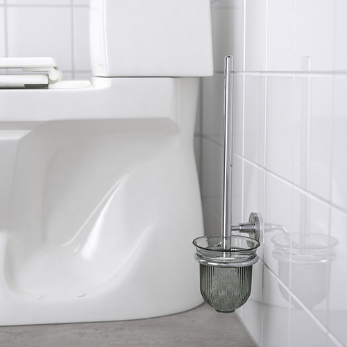 Un portaescobillas de inodoro cromado montado en una pared de baño con azulejos blancos, que oculta las fijaciones y mantiene el cepillo a mano y alejado del suelo.