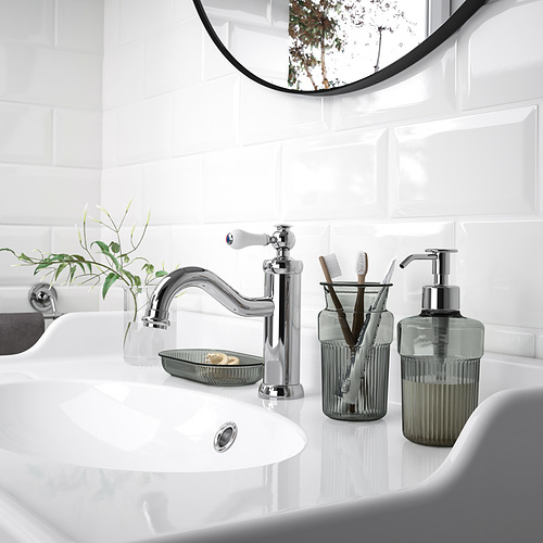 Lavabo de baño moderno con grifo cromado, dispensador de jabón verde y bandeja. Diseño minimalista.