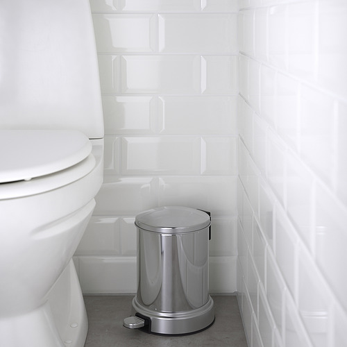 Papelera de plata en el baño junto al inodoro blanco con tapa de cierre.