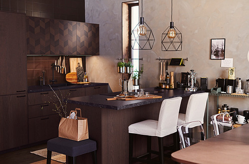 Cocina moderna con gabinetes de madera oscura, encimera de granito, taburetes de bar, luces colgantes y varios utensilios de cocina.