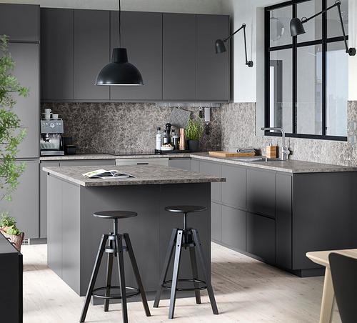 Cocina moderna con gabinetes VOXTORP gris oscuro, encimera de mármol, taburetes negros, luz colgante y electrodomésticos elegantes.