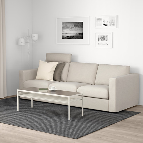 Salón minimalista con sofá VIMLE, mesa de centro, fotos de pared y lámpara de pie.