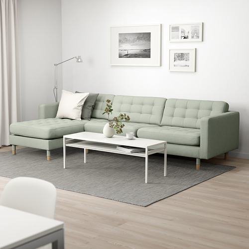 Sala de estar moderna con sofá LANDSKRONA verde, tumbona, mesa de centro blanca, alfombra gris, arte de tres paredes, lámpara de pie.