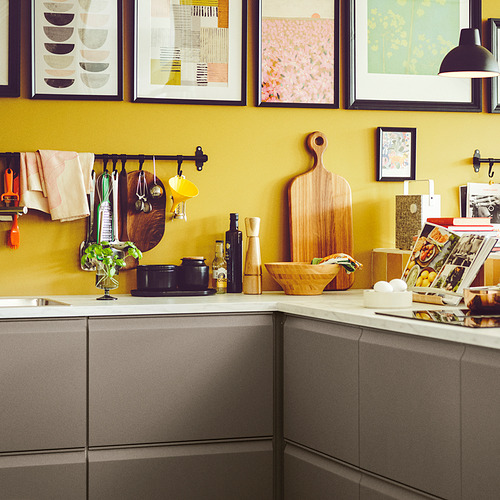 Cocina amarilla con gabinetes grises, utensilios de cocina y artículos de mostrador.