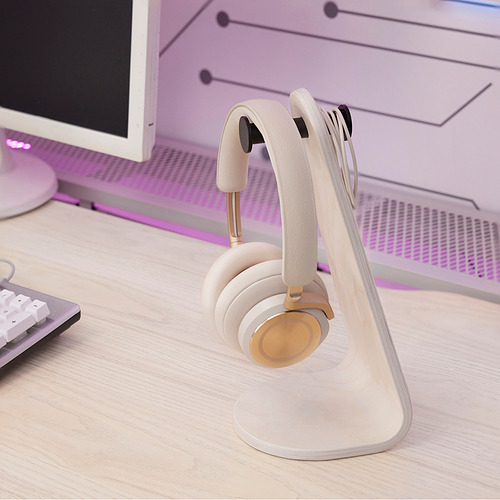 Soporte blanco para auriculares con auriculares en el escritorio cerca del teclado.