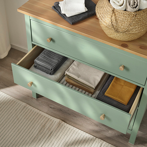 Cómoda verde abierta con ropa doblada en su interior. Organizador de cajones visible.