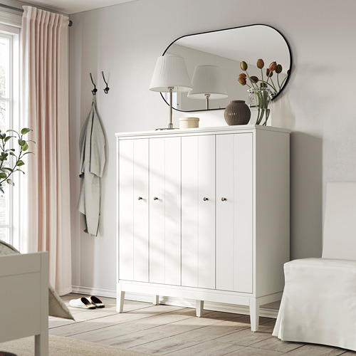 Entrada moderna con armario IDANÄS blanco, espejo, lámparas, flores, percheros y cortinas de color rosa claro.